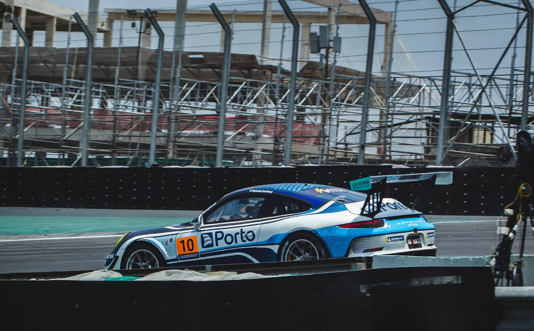 Carro azul e branco passando em frente à arquibancada